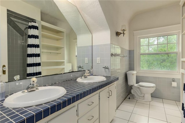 full bath with tile patterned floors, tile walls, toilet, and a sink