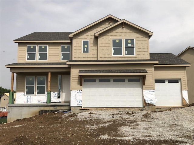 view of front of house with a shingled roof, covered porch, an attached garage, and driveway