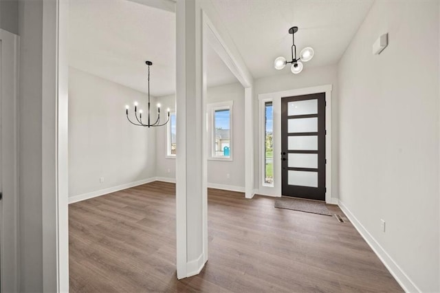 foyer featuring baseboards, a notable chandelier, and dark wood-style floors