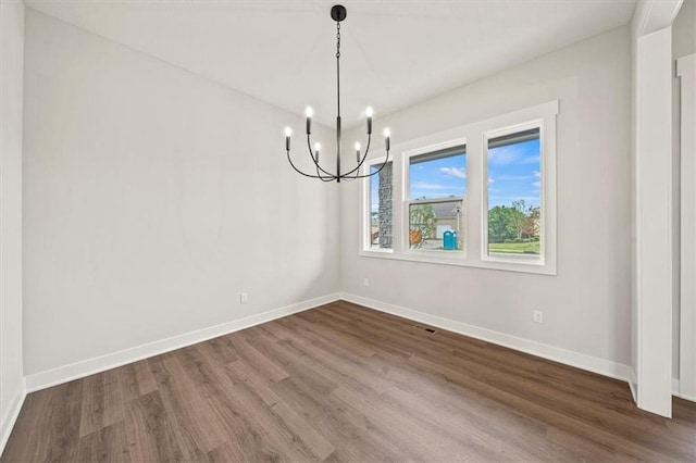 unfurnished dining area with an inviting chandelier, baseboards, dark wood-style flooring, and visible vents