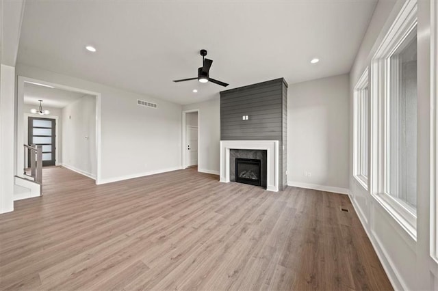 unfurnished living room featuring ceiling fan, plenty of natural light, wood finished floors, and visible vents