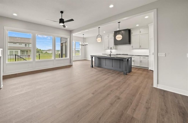 kitchen featuring a sink, tasteful backsplash, ceiling fan with notable chandelier, and white cabinetry