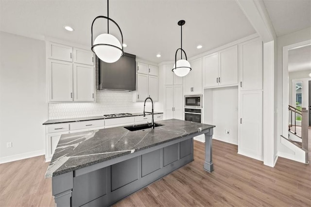 kitchen featuring a sink, light wood-style flooring, appliances with stainless steel finishes, and white cabinetry