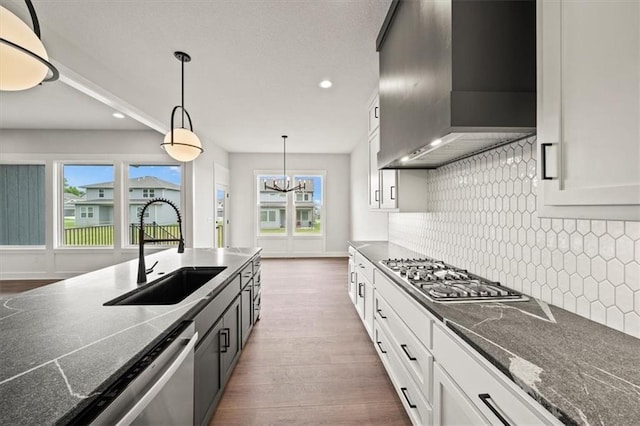 kitchen featuring dark wood finished floors, a sink, stainless steel appliances, recessed lighting, and wall chimney exhaust hood