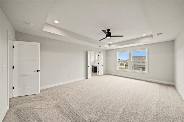unfurnished bedroom featuring a tray ceiling, baseboards, and carpet