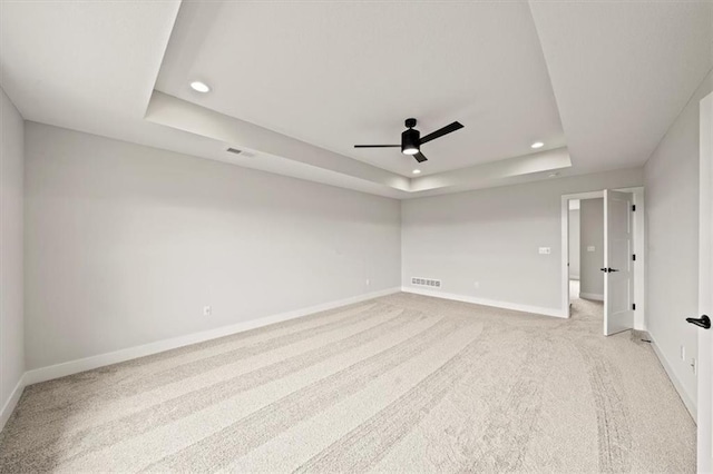 empty room with visible vents, baseboards, ceiling fan, recessed lighting, and a tray ceiling
