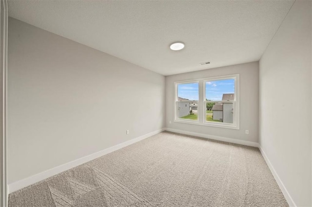 spare room with baseboards, light colored carpet, and visible vents