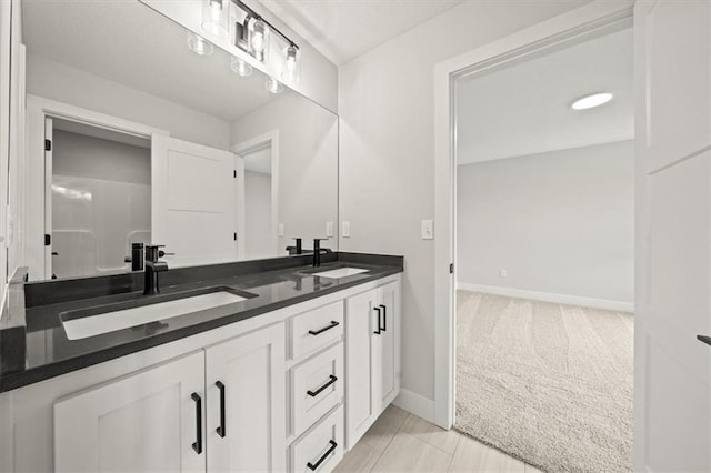 full bathroom with a sink, baseboards, and double vanity