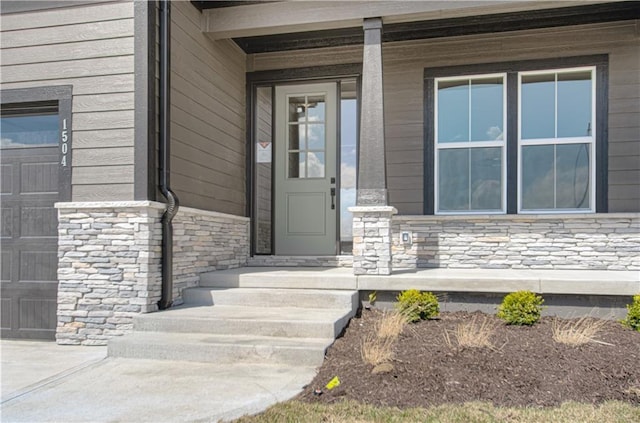 view of exterior entry featuring a garage and stone siding