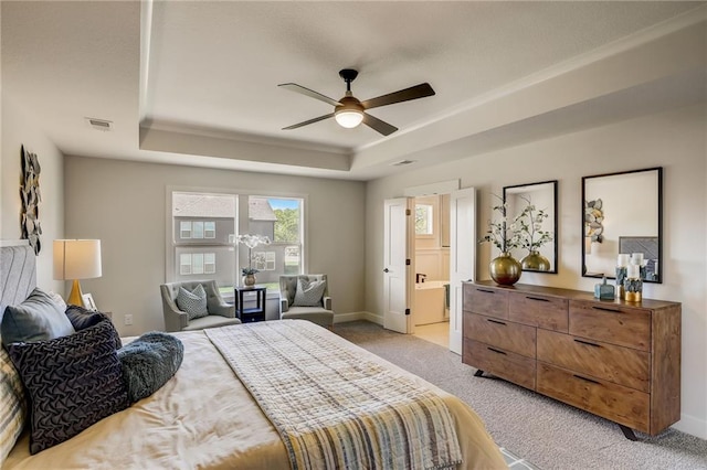 bedroom with visible vents, light colored carpet, baseboards, connected bathroom, and a tray ceiling