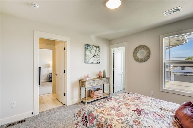 carpeted bedroom with visible vents, baseboards, and tile patterned floors