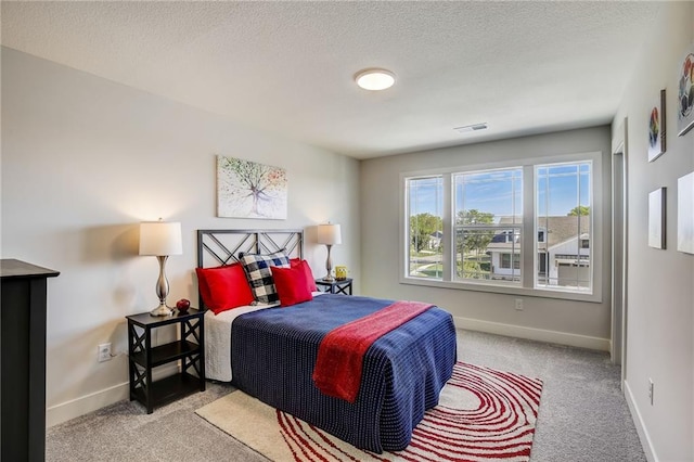 carpeted bedroom featuring visible vents, a textured ceiling, and baseboards