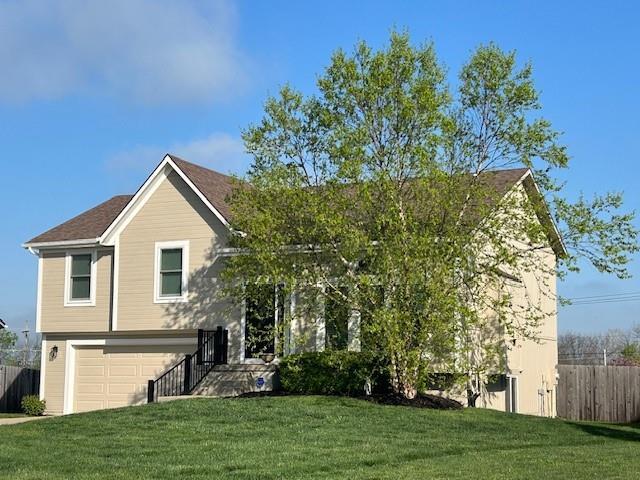 bi-level home featuring fence, an attached garage, and a front yard