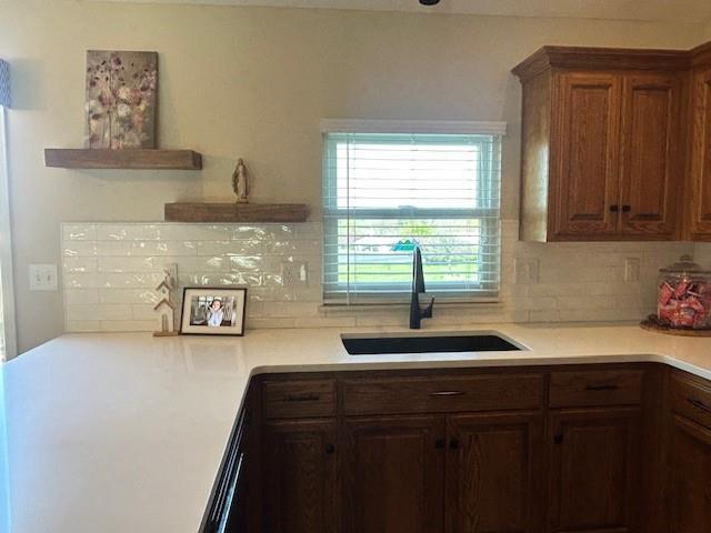 kitchen with a sink, light countertops, tasteful backsplash, and open shelves