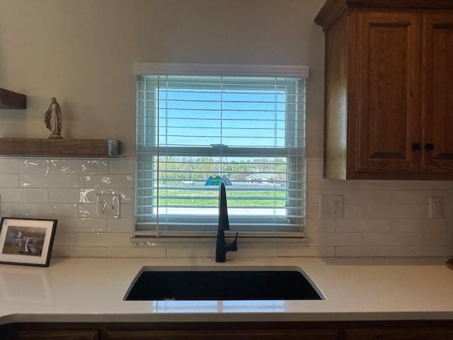 kitchen with a sink, light countertops, and tasteful backsplash