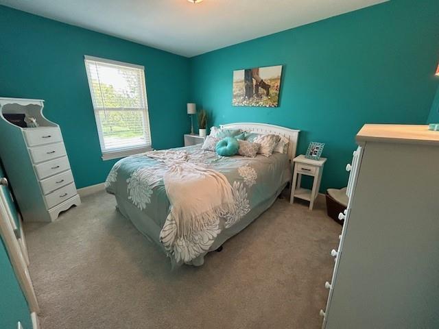 bedroom with baseboards and light carpet