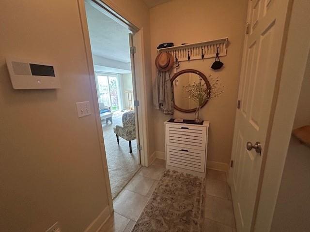 corridor with baseboards and tile patterned floors