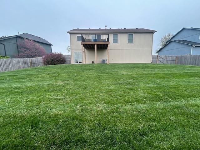 back of house featuring a fenced backyard, a wooden deck, and a yard