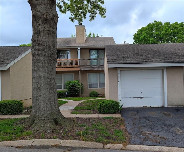 view of front of property featuring an attached garage, aphalt driveway, stucco siding, and a chimney