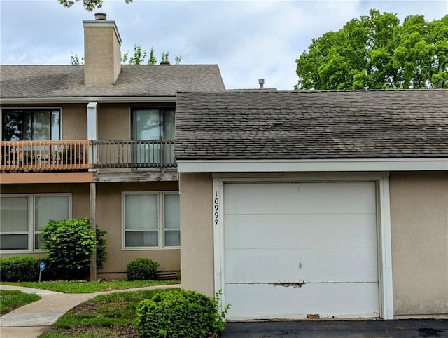 view of front of home featuring a shingled roof, a chimney, and stucco siding