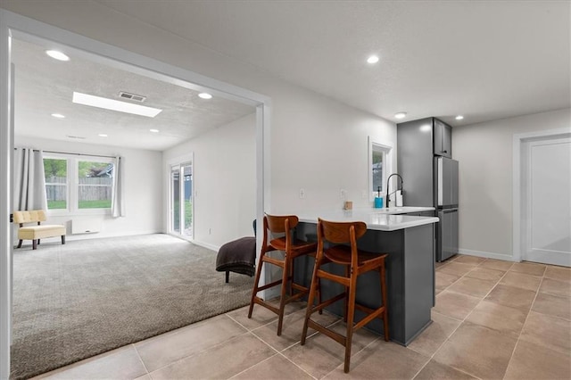 kitchen with light carpet, light countertops, freestanding refrigerator, recessed lighting, and visible vents