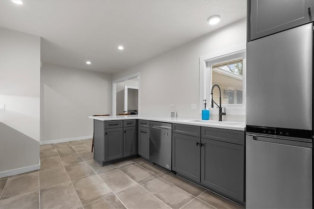 kitchen featuring a peninsula, recessed lighting, a sink, appliances with stainless steel finishes, and gray cabinetry