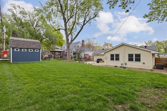 view of yard with an outdoor structure, fence, a storage unit, central AC unit, and a patio area