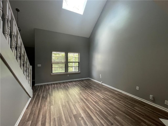 unfurnished living room featuring baseboards, dark wood-style floors, high vaulted ceiling, and stairway