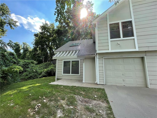 view of front of home with a shingled roof, an attached garage, driveway, and a front yard
