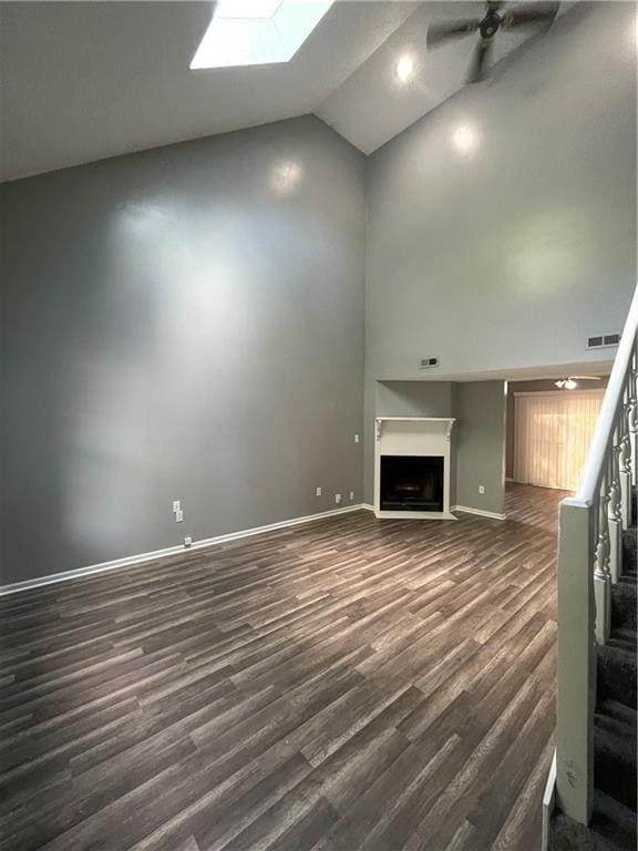 unfurnished living room with high vaulted ceiling, a fireplace, a ceiling fan, and dark wood finished floors