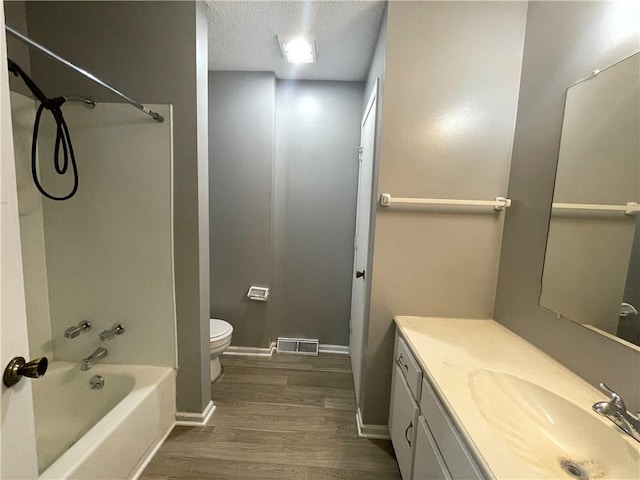 bathroom featuring visible vents, vanity, wood finished floors, toilet, and a textured ceiling