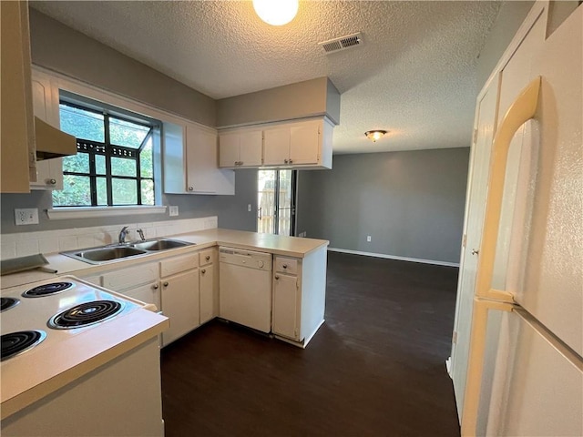 kitchen featuring visible vents, a sink, light countertops, a peninsula, and white appliances
