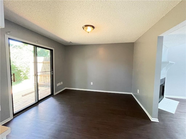 spare room featuring dark wood-style flooring, a textured ceiling, and baseboards