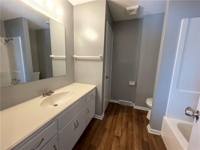 bathroom featuring baseboards, a textured ceiling, wood finished floors, and toilet