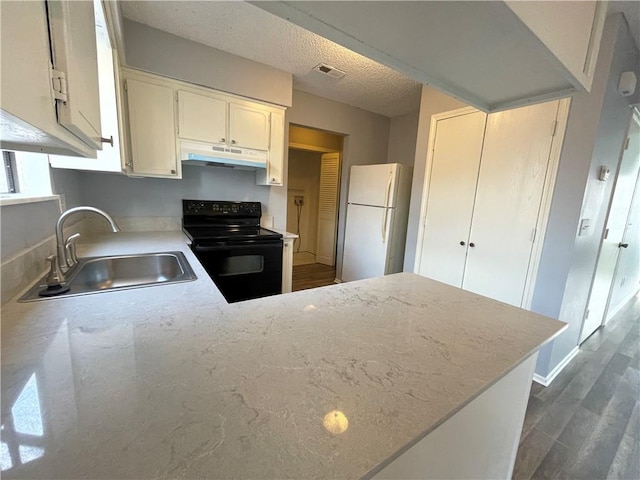 kitchen featuring visible vents, a sink, freestanding refrigerator, under cabinet range hood, and black range with electric cooktop