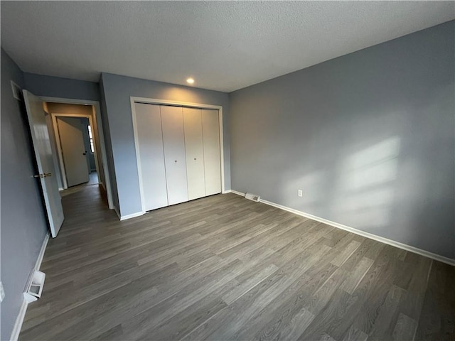 unfurnished bedroom featuring baseboards, recessed lighting, dark wood finished floors, and a closet