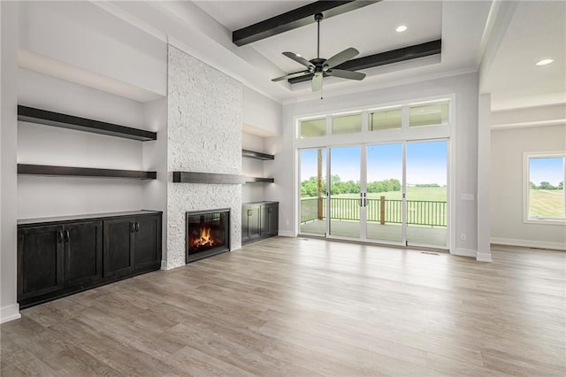 10075 NW Hillsboro Rd, Platte City, MO 64079 - unfurnished living room with a fireplace, beamed ceiling, light wood-style floors, ceiling fan, and a high ceiling