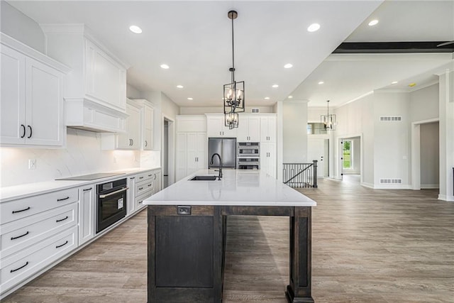 10075 NW Hillsboro Rd, Platte City, MO 64079 - kitchen featuring white cabinetry, recessed lighting, an island with sink, light wood finished floors, and backsplash