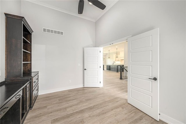 10075 NW Hillsboro Rd, Platte City, MO 64079 - unfurnished living room featuring a ceiling fan, crown molding, light wood-style flooring, and a towering ceiling
