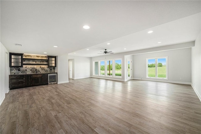 10075 NW Hillsboro Rd, Platte City, MO 64079 - unfurnished living room with wine cooler, wood finished floors, bar, recessed lighting, and ceiling fan