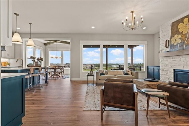 17163 S Laurelwood St, Olathe, KS 66062 - living room with a chandelier, a stone fireplace, dark wood-style flooring, and recessed lighting