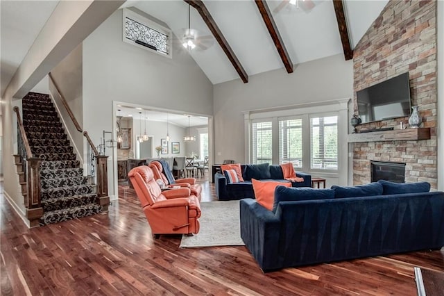 living area featuring stairs, wood finished floors, a stone fireplace, high vaulted ceiling, and a ceiling fan