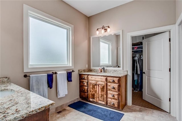 bathroom with vanity, a spacious closet, and visible vents