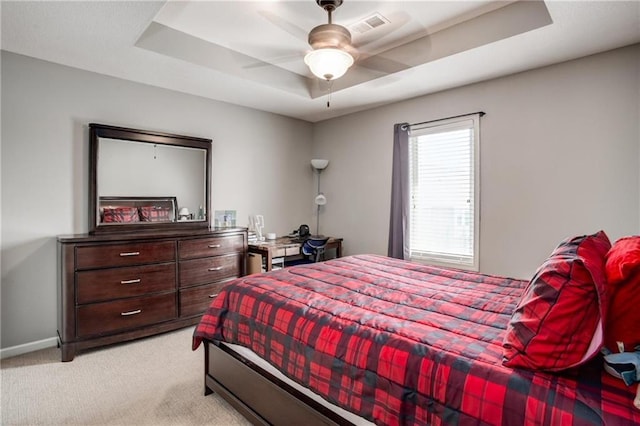 bedroom with visible vents, baseboards, ceiling fan, light colored carpet, and a raised ceiling