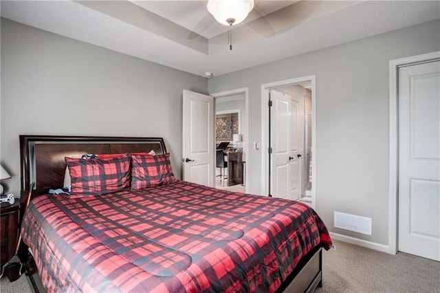 bedroom featuring baseboards, carpet, ensuite bath, and visible vents