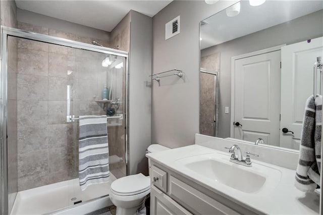 bathroom with toilet, visible vents, a shower stall, and vanity
