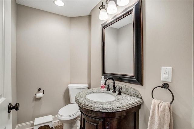 bathroom featuring toilet, baseboards, and vanity