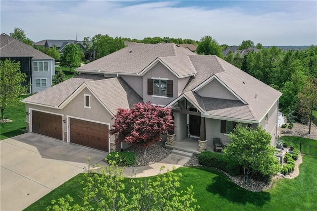 craftsman-style house featuring a garage, a front lawn, fence, stucco siding, and driveway