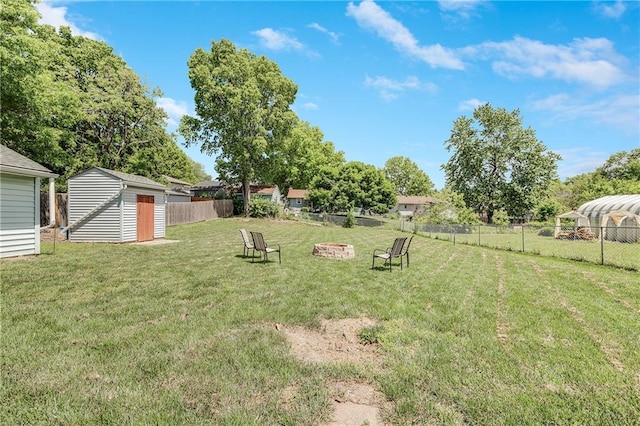 view of yard featuring a storage unit, an outdoor structure, and a fire pit