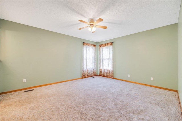 carpeted empty room with a ceiling fan, baseboards, and a textured ceiling